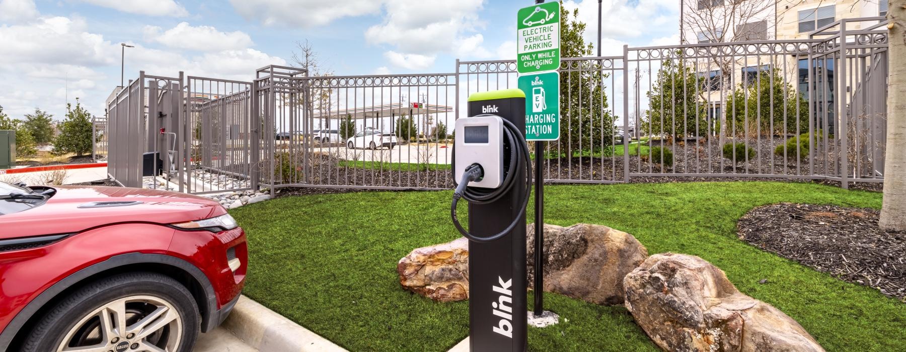 a red car parked next to a electric car charging station